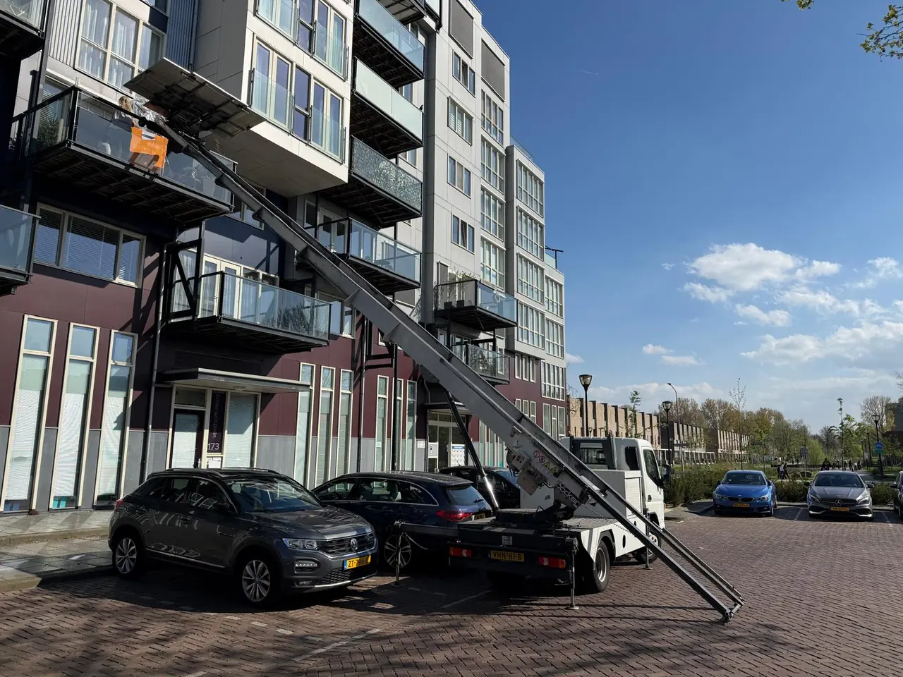 Volledige opstelling: vrachtwagen, ladder en flatgebouw
